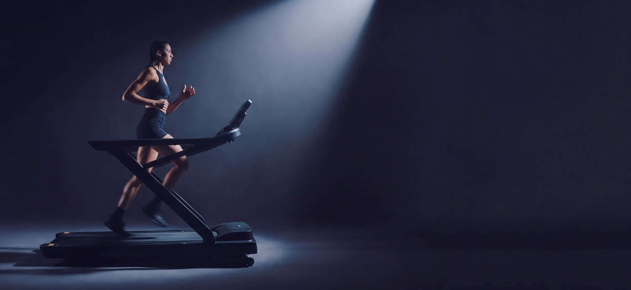 Athlete running on a treadmill under a spotlight